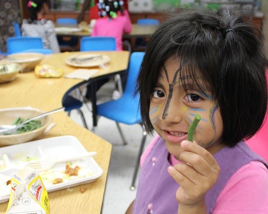 PHOTO: A Minnesota student enjoys locally grown green beans as part of a Farm to Preschool celebration. Photo courtesy of Institute for Agriculture and Trade Policy.