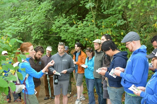 PHOTO: Amy Kaeser with Friends of Cedar River Watershed talks with brewers from Fremont Brewing, Schiling's Cider and Naked City Brewing about native plants in Seattle's Discovery Park. Credit: Dani Kendall.