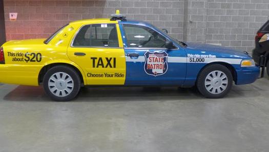 PHOTO: This car was painted up by Wisconsin law enforcement authorities to graphically demonstrate the difference in dollar cost between taking a taxi home after having had too much to drink, rather than put the public at risk by drunken driving and getting arrested for it. (Photo credit: Gilman Halsted, WPR)