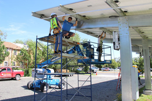 Workers install a new solar panel array at the 