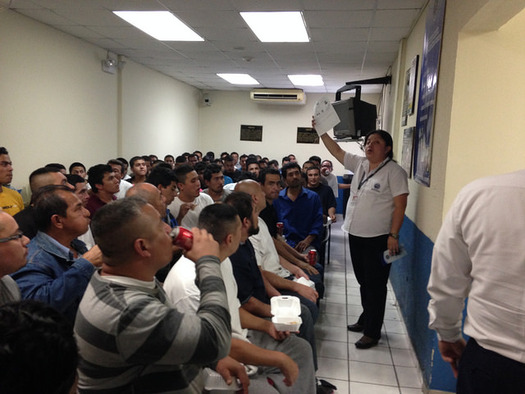 Deportees from the United States crowd into a small room to receive information from an immigration official in El Salvador. (Fronteras Desk/flickr)