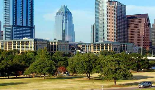 A stand of live oak trees in Butler Park frames the downtown Austin skyline. Conservationists say urban forests are critical to air and water quality in Texas cities. (Wikimedia Commons)