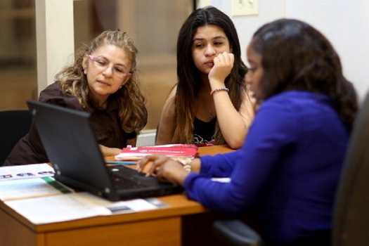 A volunteer assists a mother and daughter in signing up for health insurance through the Affordable Care Act. (Raedle/GettyImages) 