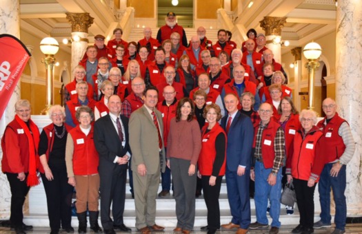 Clad in their signature red vests, members of AARP South Dakota shared their priorities with Gov. Kristi Noem, front row center, during Lobby Day at the State Capitol. (aarp.org/sd)