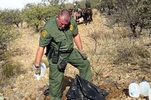 A U.S. Border Patrol officer opens and drains a water bottle left by No More Deaths volunteers to help migrants in the Agua Prieta National Wildlife Refuge in 2017. (NoMoreDeaths)