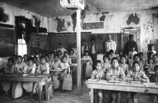 Native American students, most of them barefoot, sit for lessons in a crowded classroom inside the Walapai Indian School in Kingman, Ariz., circa 1900. (Wikimedia Commons)