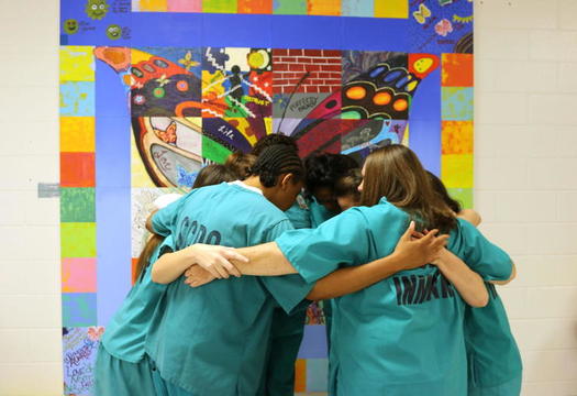 Incarcerated women who participated in the Prisoners Too art project hug in front of the installation at a South Carolina prison. (South Carolina Department of Corrections)