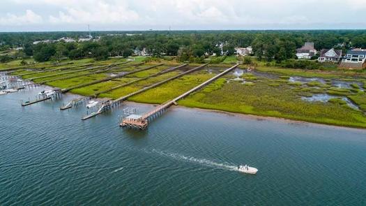 (A drone photograph shows residential docks spanning a salt marsh in Wrightsville Beach. Salt marshes in North Carolina are being pushed back by rising sea waters, but aren't always able to retreat because of coastal development, leaving them to shrink. (Travis Long)