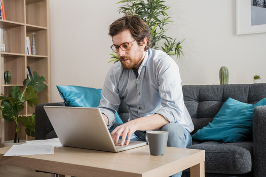 Working from household furniture that's not ergonomically designed can contribute to back pain. (Paolese/Adobe Stock)
