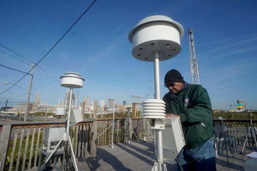 Carleton See, an environmental monitoring specialist, changes filters on an air monitoring device at the George T. Craig Air Quality Monitoring Site in downtown Cleveland. (Gus Chan for Eye on Ohio)