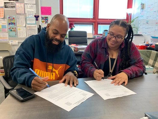 Jermaine Bailey and daughter ShaWanna sign their letters of job offers with the city of York's school district. Both are certified teachers and will start in the Fall. (Courtesy Jermaine Bailey)
