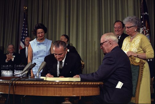 Former President Harry Truman was present when President Lyndon Johnson enacted Medicare. (White House Press Office)
