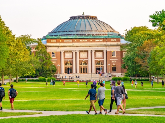 College students walk on the quadrangle lawn of the Foellinger Auditorium on the University of Illinois campus in Urbana. (Adobe Stock)