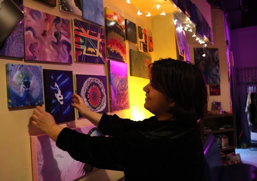 Anj Karna, director of Fargo's community art space Parachigo, rearranges art for sale. (Photo courtesy of Amy Felegy).