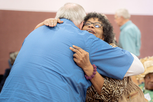 Two Open Book participants embrace after an Open Book event held to connect their respective churches in Des Moines. (Arts Midwest) 