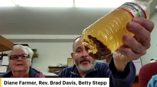 A McDowell County, West Virginia resident holds up a water bottled filled with brown tap water at a webinar hosted by ReImagine Appalachia. (Facebook/ReImagine Appalachia)