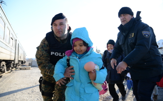 Macedonia police agents help a refugee mother and daughter in transit through the European country. (New Partners)