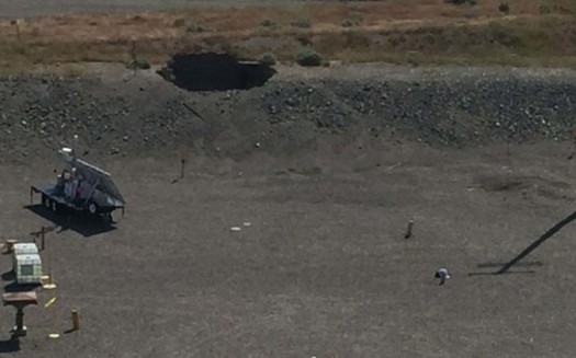 A large hole, seen at the top of the picture, developed over a tunnel at the Hanford site. The tunned contains rail cars containing radioactive waste. (U.S. Department of Energy)