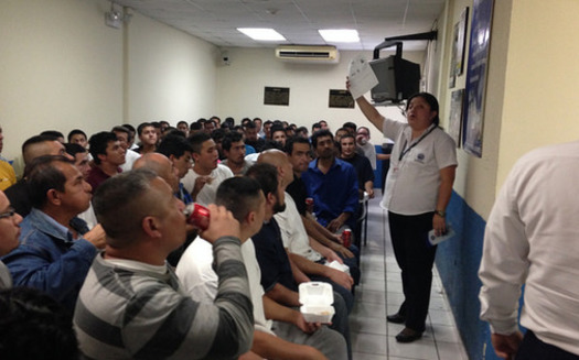 Deportees from the United States crowd into a small room to receive information from an immigration official in El Salvador. (Fronteras Desk/flickr)