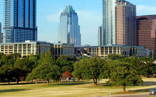 A stand of live oak trees in Butler Park frames the downtown Austin skyline. Conservationists say urban forests are critical to air and water quality in Texas cities. (Wikimedia Commons)