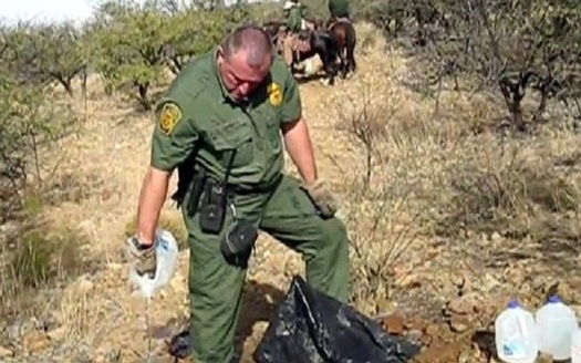 A U.S. Border Patrol officer opens and drains a water bottle left by No More Deaths volunteers to help migrants in the Agua Prieta National Wildlife Refuge in 2017. (NoMoreDeaths)