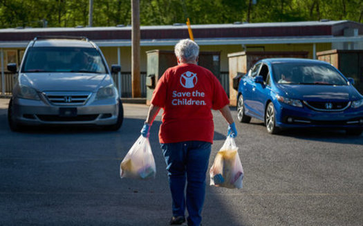 At a drive-up distribution, a Save the Children staff member hand-delivers food to children and families. (Shawn Millsaps/Save the Children)
