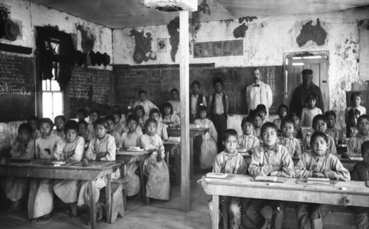 Native American students, most of them barefoot, sit for lessons in a crowded classroom inside the Walapai Indian School in Kingman, Ariz., circa 1900. (Wikimedia Commons)