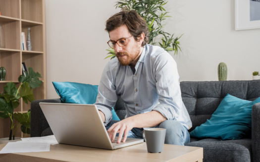Working from household furniture that's not ergonomically designed can contribute to back pain. (Paolese/Adobe Stock)
