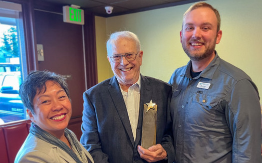Tom Oliver, center, receives the 2022 Washington Andrus Award for Community Service. (Bruce Carlson/AARP Washington)