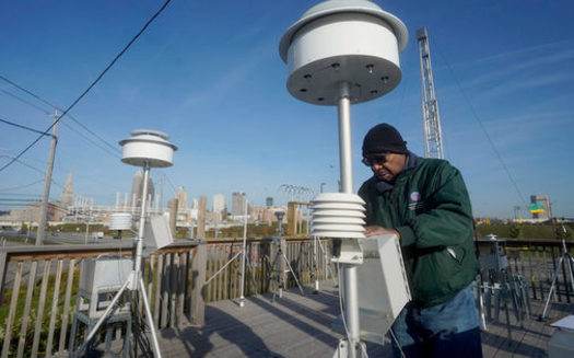Carleton See, an environmental monitoring specialist, changes filters on an air monitoring device at the George T. Craig Air Quality Monitoring Site in downtown Cleveland. (Gus Chan for Eye on Ohio)