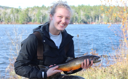 University of Maine graduate Emily Miller holds a female Arctic charr from the Floods Pond field site in Otis, Maine, where she and other scientists will measure, genetically sample and tag the long-lived species with a microchip ID. (Bradley Erdman)