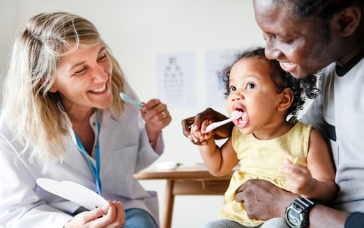 According to the CDC, children who regularly see a dentist and brush daily with a fluoride toothpaste are likely to have fewer dental problems as adults. (Rawpixel/Adobe Stock)
