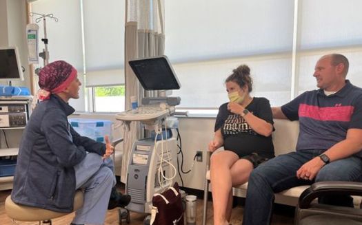 Labor and Delivery doctor Taylor Swartz talks with a pregnant patient and her husband at Mahaska Health Hospital in Iowa. (Tony Leys/KFF Health News) 