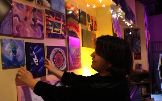 Anj Karna, director of Fargo's community art space Parachigo, rearranges art for sale. (Photo courtesy of Amy Felegy).