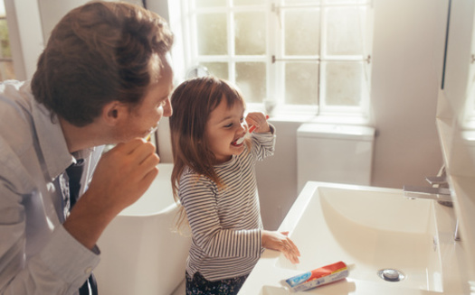 Adults can model proper brushing for their children by brushing alongside them. (Jacob Lund/Adobe Stock)