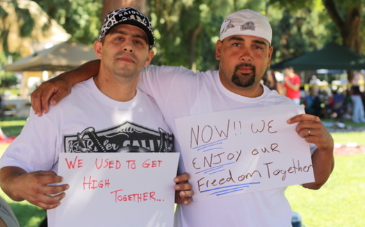 PHOTO: Two men hold signs describing how treatment and recovery has changed their lives. A new state audit says only about half of those released from prison who need substance abuse treatment are getting it. Courtesy PSJ.